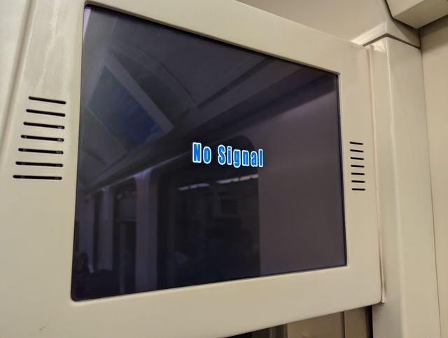 An LCD screen mounted on a white panel displaying the message "No Signal" in blue text against a black background.